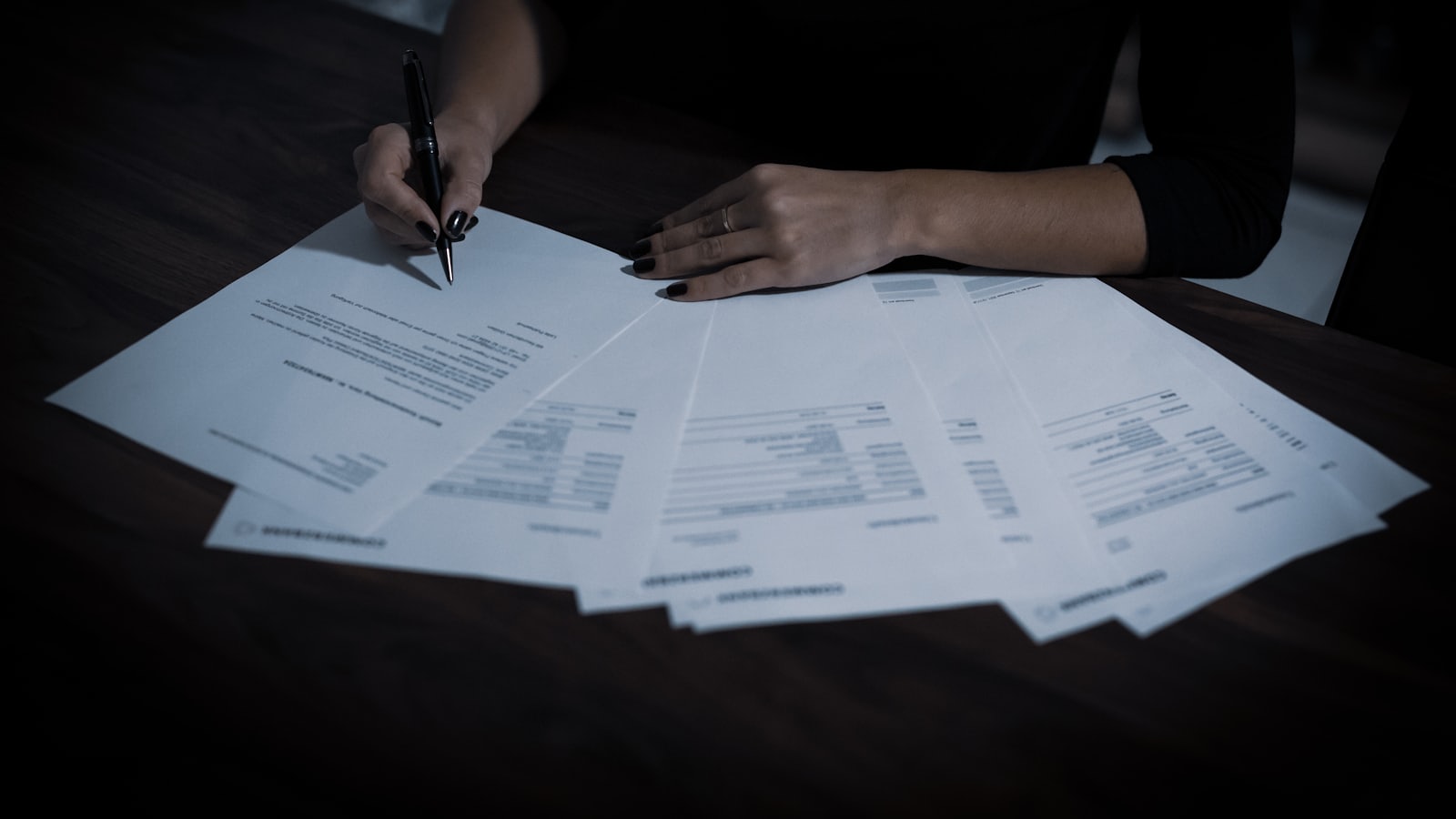 signed papers spread across a dark desk